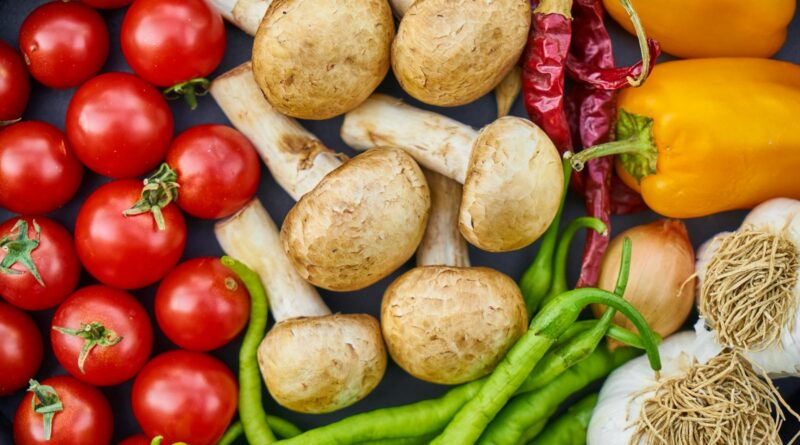 A vibrant assortment of fresh vegetables and mushrooms arranged in a flat lay.