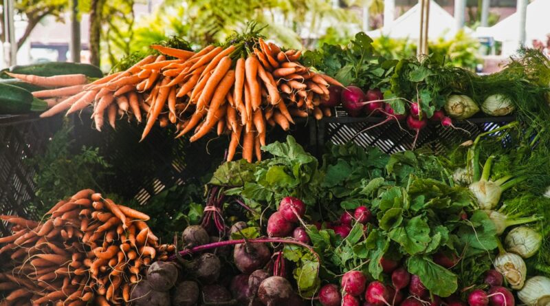 A vibrant display of fresh carrots, radishes, and greens at a local outdoor market.